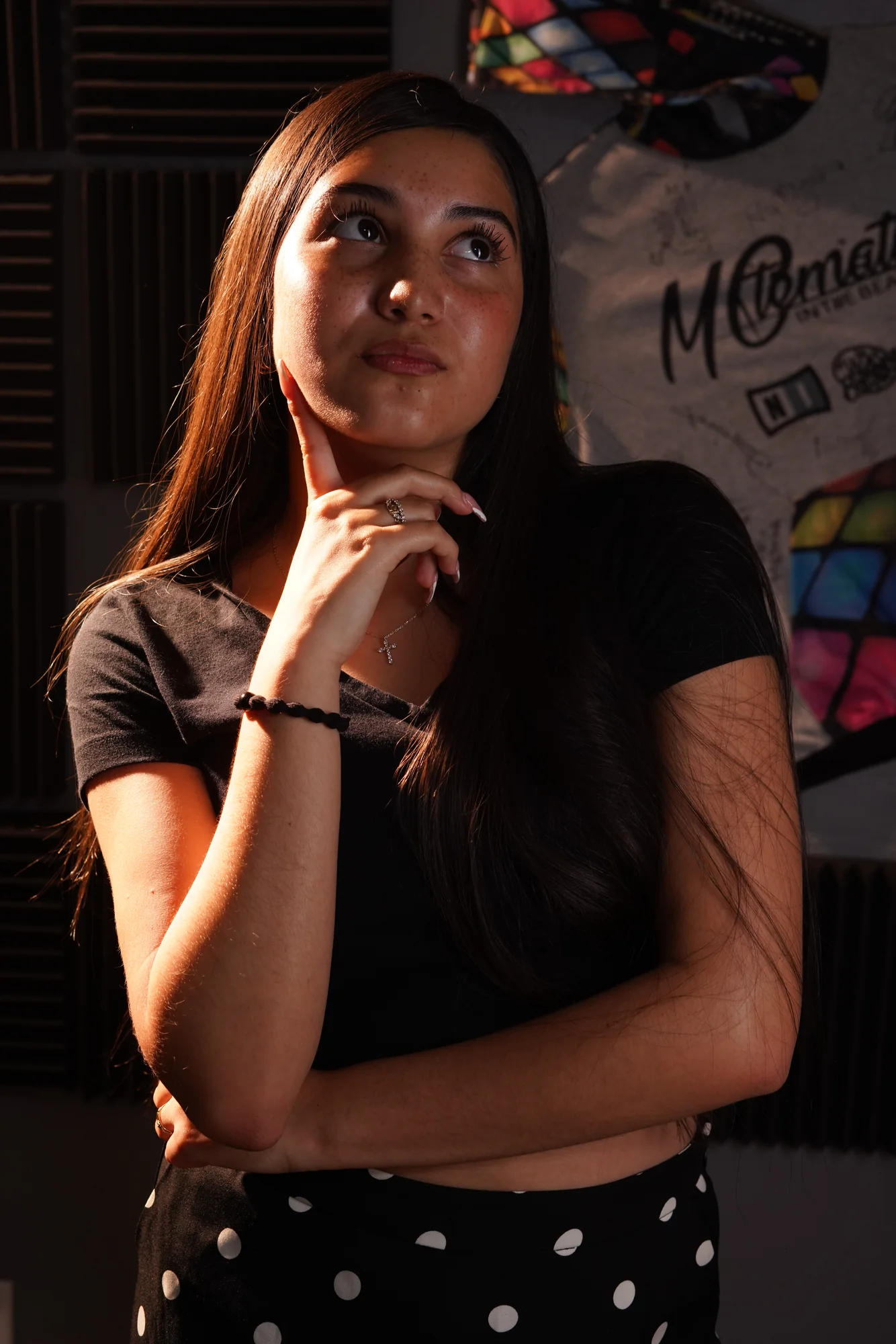 Abigail V. in the studio, hand at her chin, looking upward in thought.